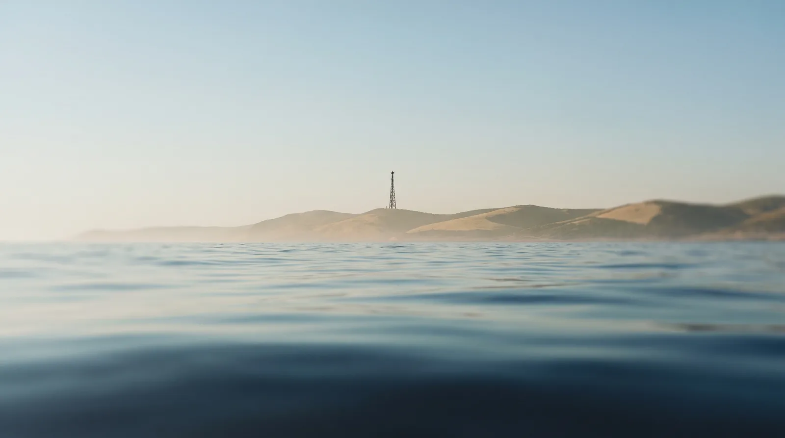 Côte vue depuis le large, un pylône se détache à l'horizon